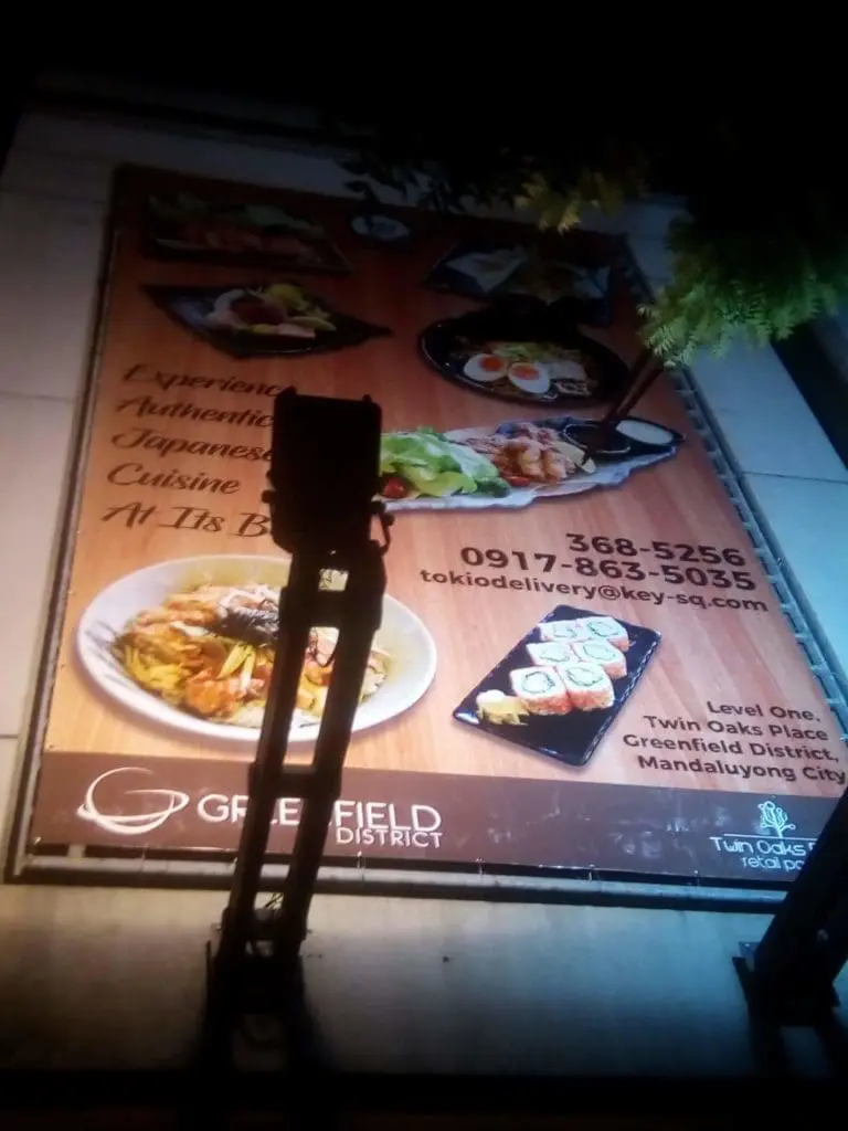 Outdoor restaurant signage for Japanese dishes with contact info in Ortigas, partially blocked by a pole, by M&G Global Ads.