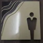 Acrylic restroom signage with person icon, three curved lines, on dark wood in Makati by M&G Global Ads.