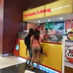 Two women at a Tteokbokki & Odeng stall with yellow and red LED signage in Quezon City by M&G Global Ads.