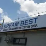 Outdoor business signage for DREAM BEST Academy in Quezon City, workers installing by Philippine flag and sky, by M&G Global Ads.