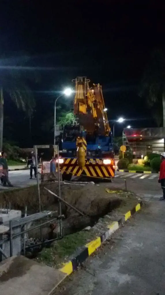 Crane truck at Makati construction site with workers, safety barriers, acrylic signage by M&G Global Ads.