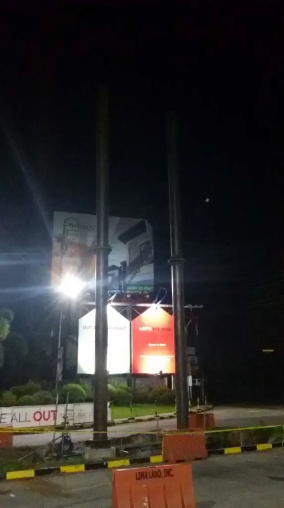 Metal billboard structures for advertising on a Makati roadside at night, construction barriers visible, by M&G Global Ads.