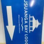 Outdoor sign for Busuanga Bay Lodge in Makati shows white left arrow, pier illustration, and slogan. By M&G Global Ads.