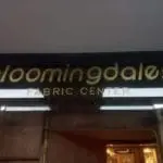 Building signage for Bloomingdales Fabric Center in Makati, gold letters above entrance, dim store interior, by M&G Global Ads.
