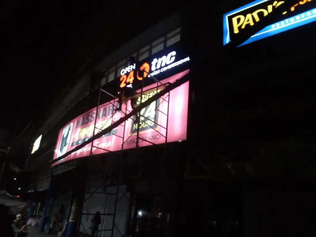 Open 24 TNC metallic storefront sign installation in Makati at night with illuminated signage by M&G Global Ads.