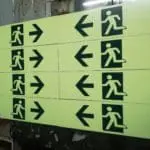 Metallic emergency exit signs set with left-pointing arrows, yellow background, in Makati by M&G Global Ads.