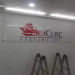 Acrylic metallic signage for SeaCure Freight Inc. with logo in a well-lit Makati room, ladders in front, by M&G Global Ads.