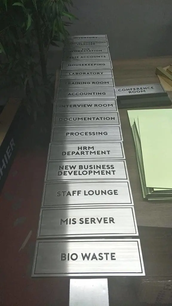 Metallic office door signage for various departments displayed on a table in Makati by M&G Global Ads.