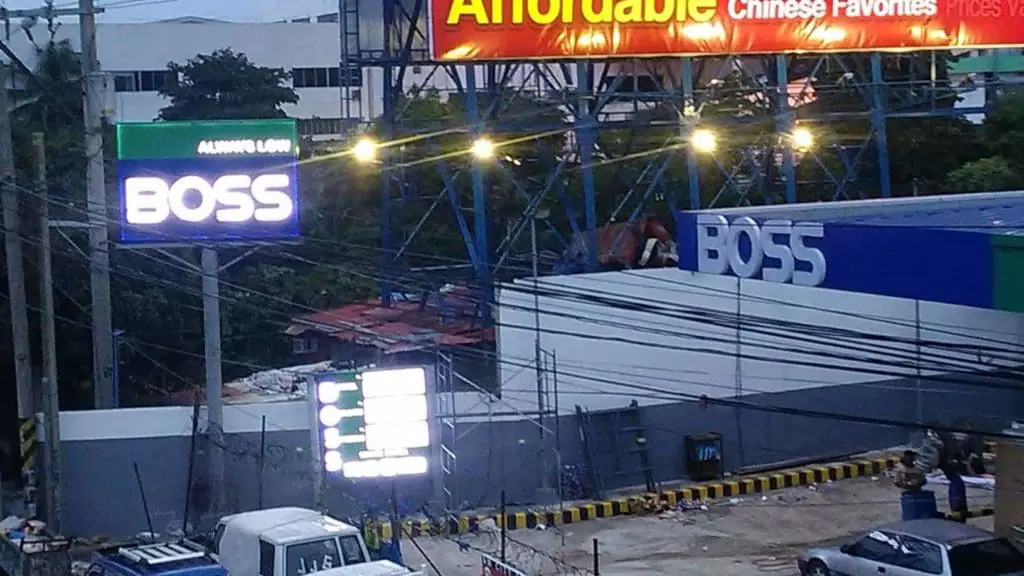 BOSS metallic building signage and LED billboard in Makati, streetlights and vehicles visible, by M&G Global Ads.