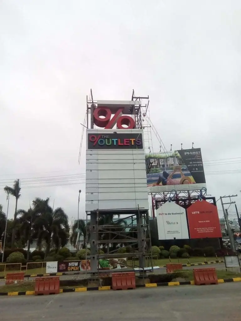 Roadside pylon signage for The Outlets with red percent symbol under construction in Pasig, by M&G Global Ads.