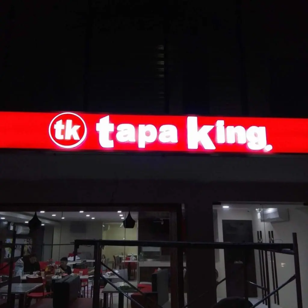 Illuminated metallic restaurant signage for Tapa King in Quezon City, with people inside. By M&G Global Ads.
