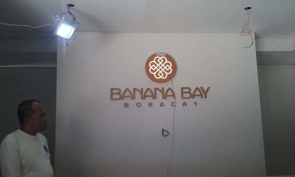 Acrylic signage for Banana Bay Boracay client shown in Makati, gold logo and emblem, installation by M&G Global Ads.