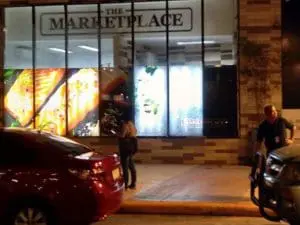 The Marketplace LED store signage with food images in Makati at night, people on sidewalk, by M&G Global Ads.