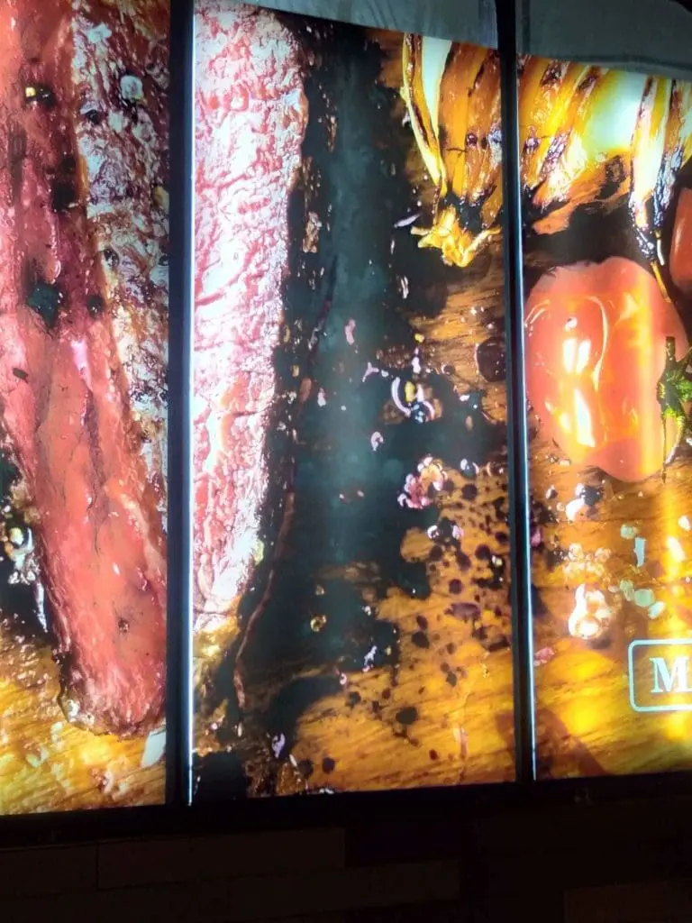 Metallic restaurant signage showing grilled steak and veggies, backlit in Makati, by M&G Global Ads.