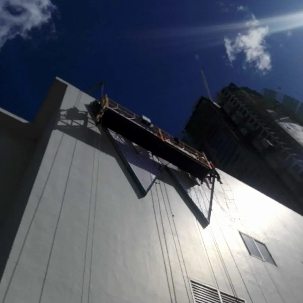 High-rise billboard installation on a tall building in Makati with scaffold, ropes, and safety nets by M&G Global Ads.