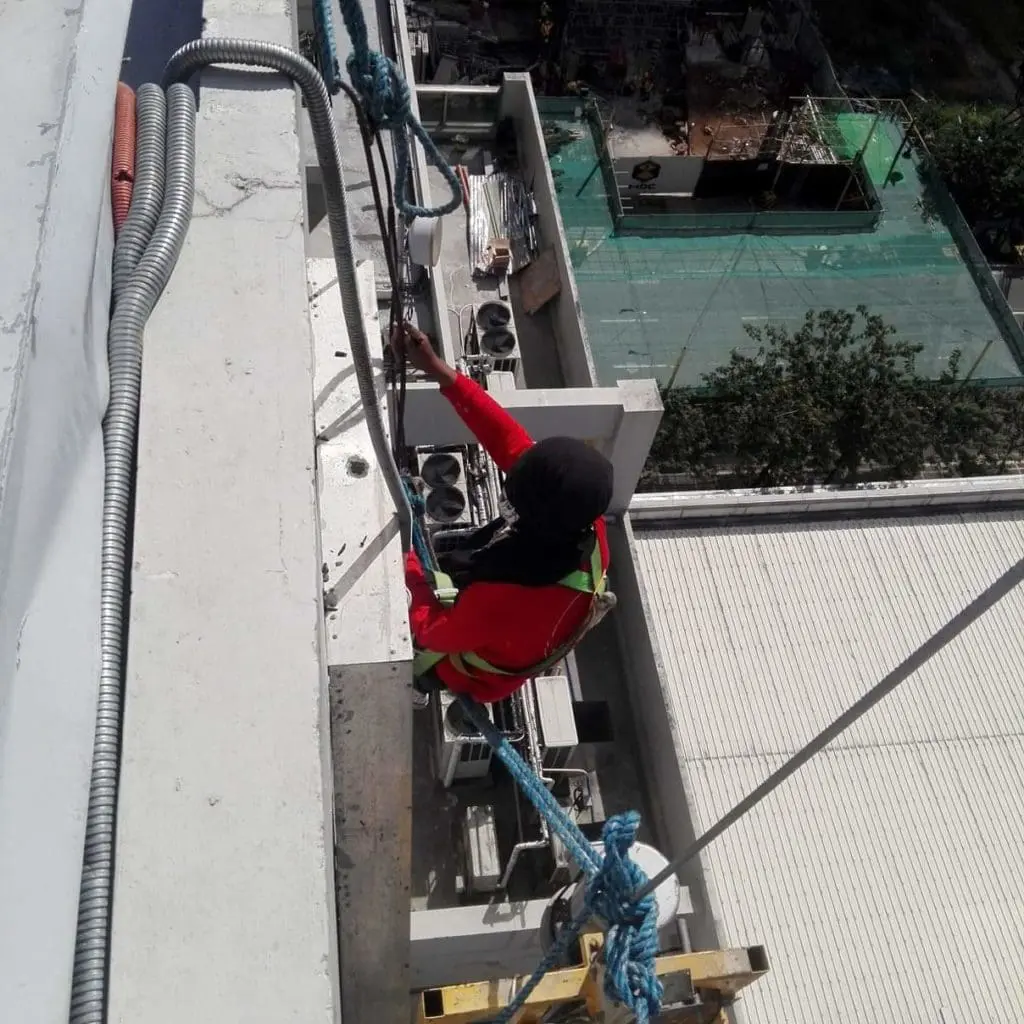 LED billboard signage installation in Makati—worker in harness on building edge with equipment by M&G Global Ads.