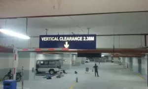 Parking garage clearance signage showing 2.38M in Makati with cars below, by M&G Global Ads.