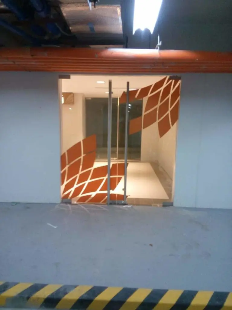 Indoor glass door signage with orange geometric design in Mandaluyong, industrial-style room, by M&G Global Ads.