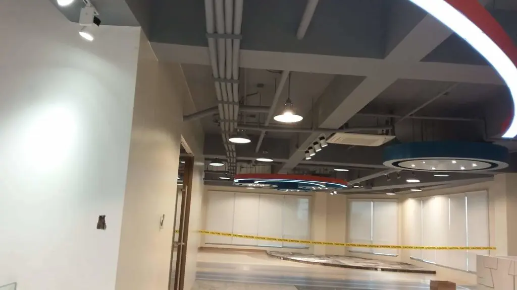 Office interior signage installation in progress, modern Makati office, exposed pipes, branded metal signs by M&G Global Ads.
