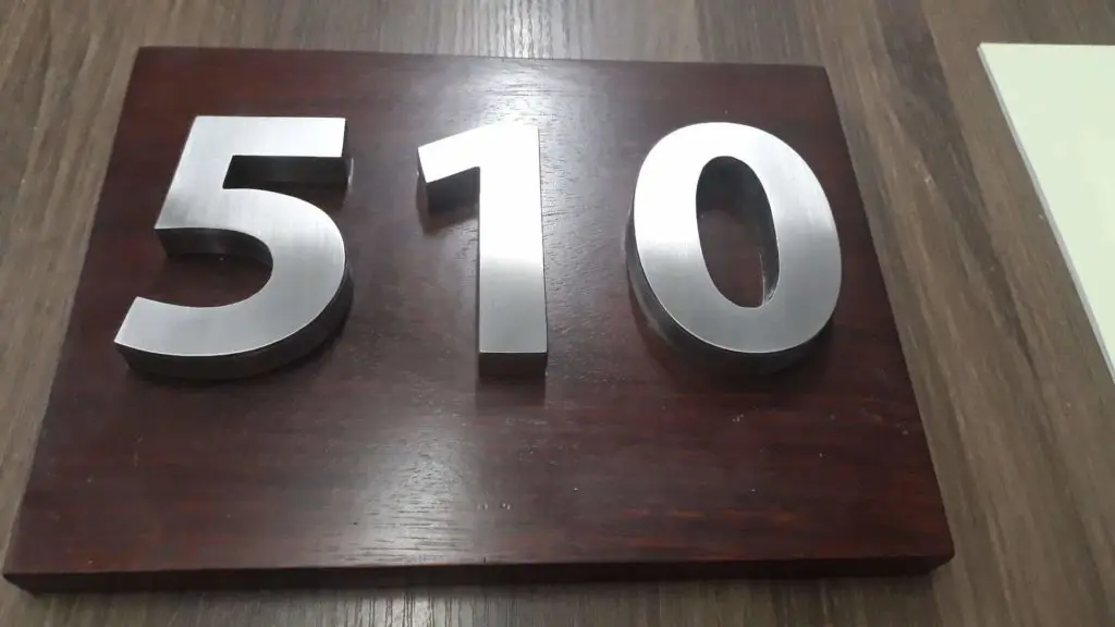 Metallic building number signage 510 on dark wood plaque in Makati, displayed on wood surface by M&G Global Ads.