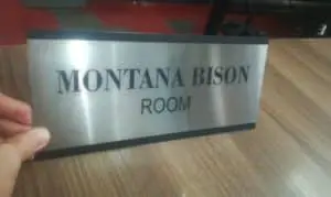 Indoor metallic room sign for Montana Bison Room in Makati, bold black letters, held by hand on table by M&G Global Ads.