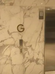 Lobby directory signage with a golden letter G above elevator buttons in Makati, by M&G Global Ads.