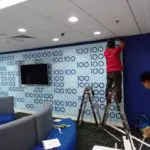Office acrylic wall signage installation for corporate client in Ortigas: team working on blue accent wall by M&G Global Ads.