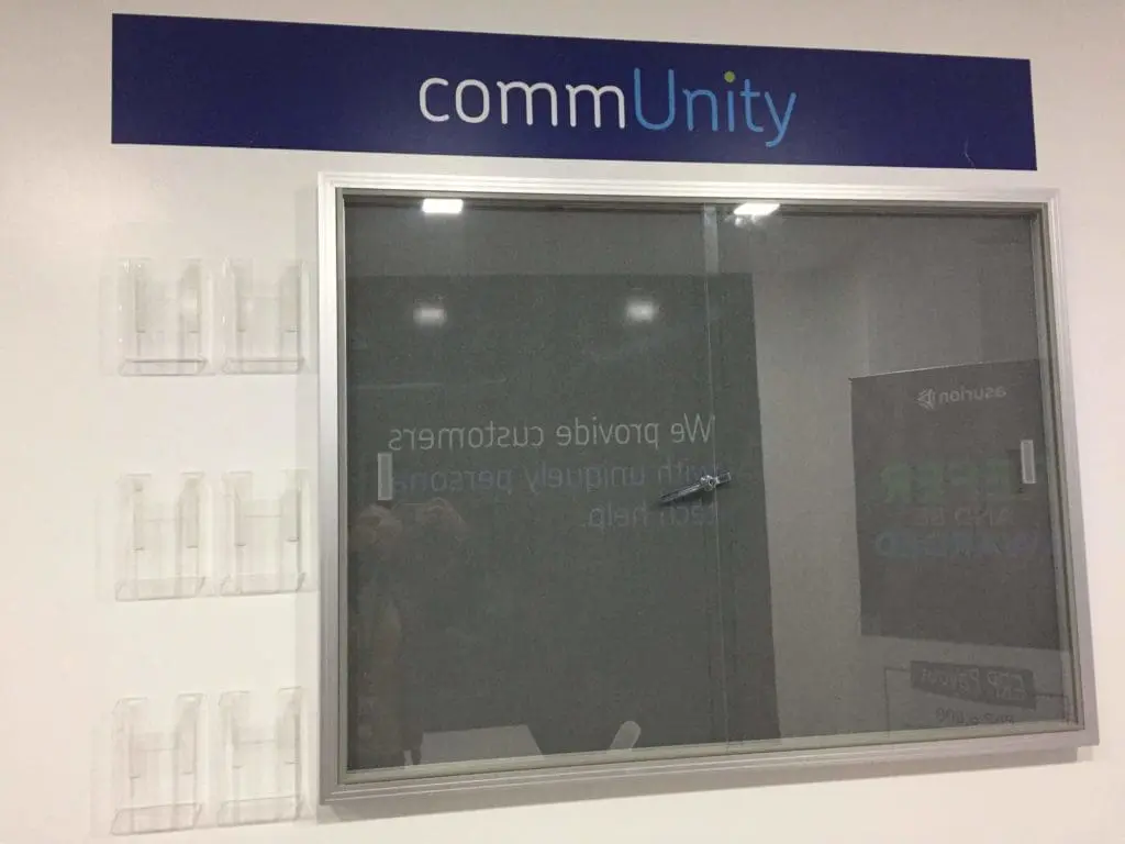 Metallic commUnity wall signage with brochure holders in a white Ortigas office interior by M&G Global Ads.