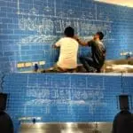 LED signage planning for restaurant, with two men sketching on a blue wall in Makati by M&G Global Ads.