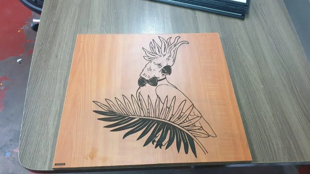 Acrylic indoor signage mockup for a Quezon City client featuring a cockatoo and tropical leaf on wood by M&G Global Ads.