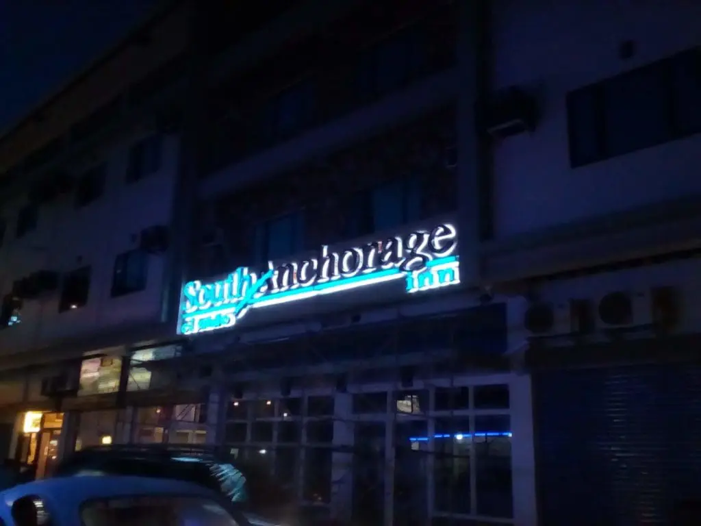 Neon outdoor signage for South Anchorage Inn on a dimly lit building with parked car in Makati by M&G Global Ads.