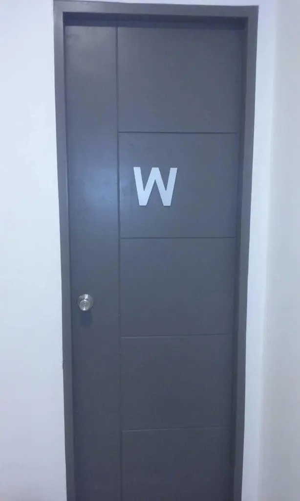 Indoor door signage with large white W and sleek silver handle in a white wall, Makati location, by M&G Global Ads.