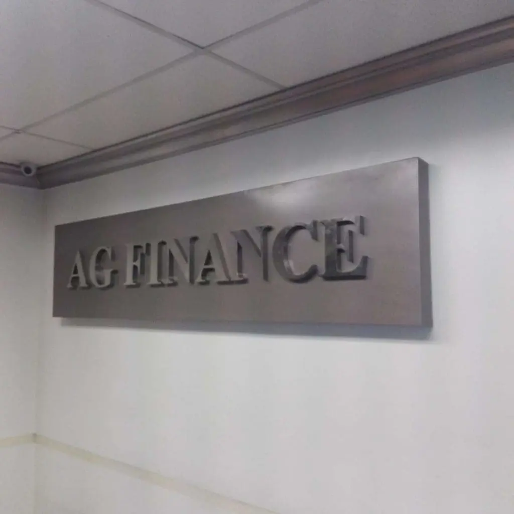 AG FINANCE metallic office signage in Makati, bold raised letters on white wall above eye level by M&G Global Ads.