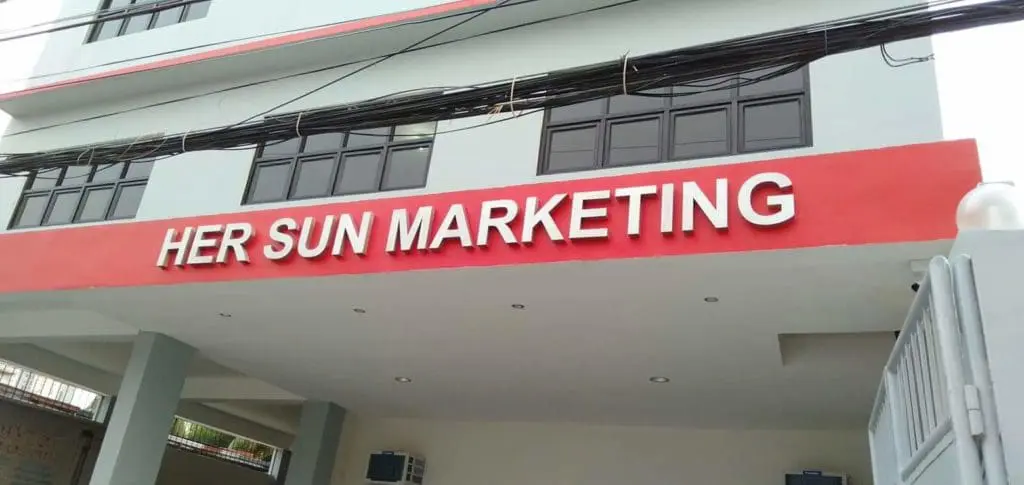 HER SUN MARKETING metallic storefront signage on a red and white facade in Quezon City by M&G Global Ads.