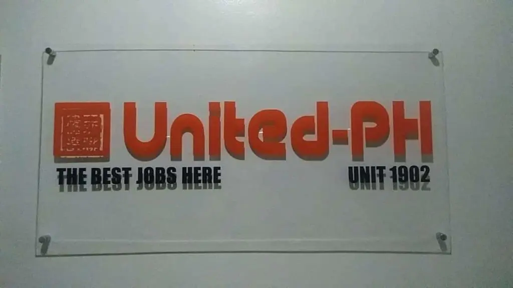 Acrylic wall signage for United-PH in Makati, bold orange letters and black text, with four fasteners by M&G Global Ads.