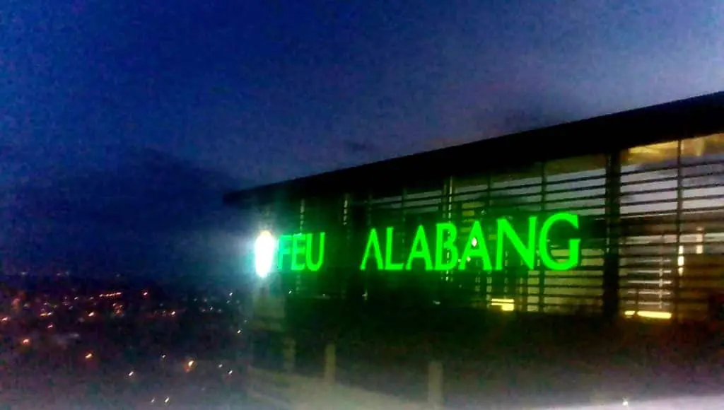 Acrylic building Signage Maker in Metro Manila by M&G Global Ads Inc. FEU ALABANG with green illuminated letters at dusk