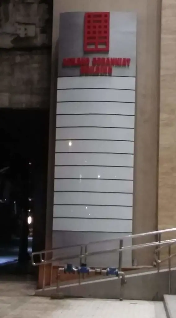 Pylon signage with horizontal white panels and red logo at building entrance in Ortigas, night view, by M&G Global Ads.