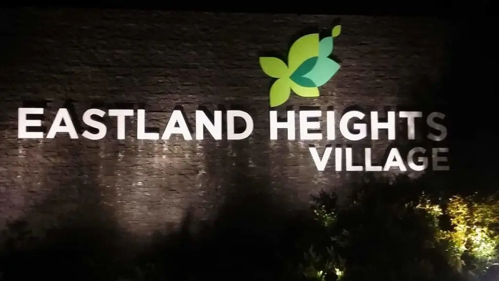 LED wall signage for Eastland Heights Village in Makati with green leaf logo and bushes, at night, by M&G Global Ads.
