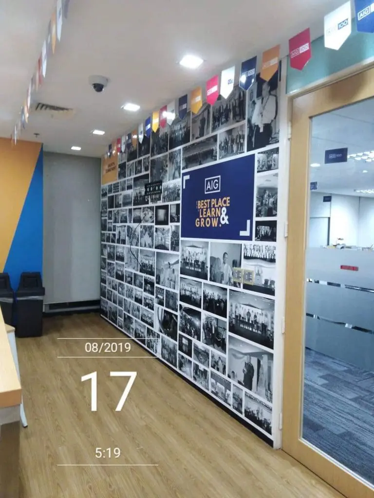 Metallic office signage for AIG in Makati, with photos, wooden floor, glass doors, flags. By M&G Global Ads.