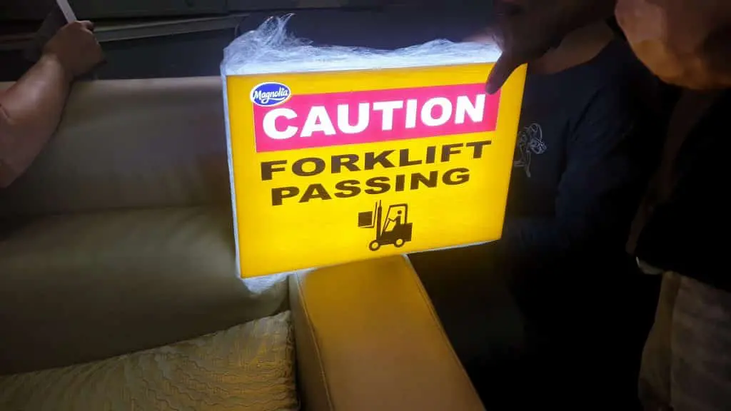 Illuminated forklift caution indoor signage in Makati, held near beige couch, by M&G Global Ads.