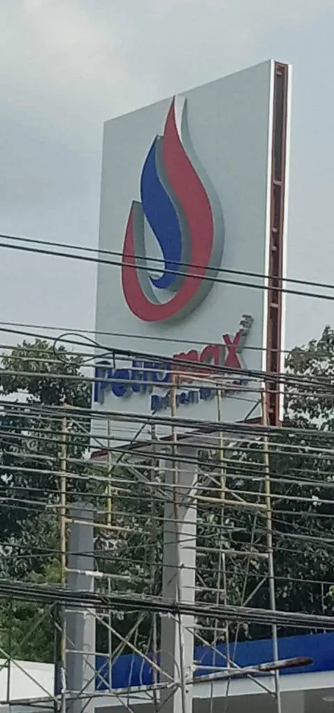 PTT Station outdoor signage metallic sign in Quezon City, partly obscured by wires and scaffolding, by M&G Global Ads.