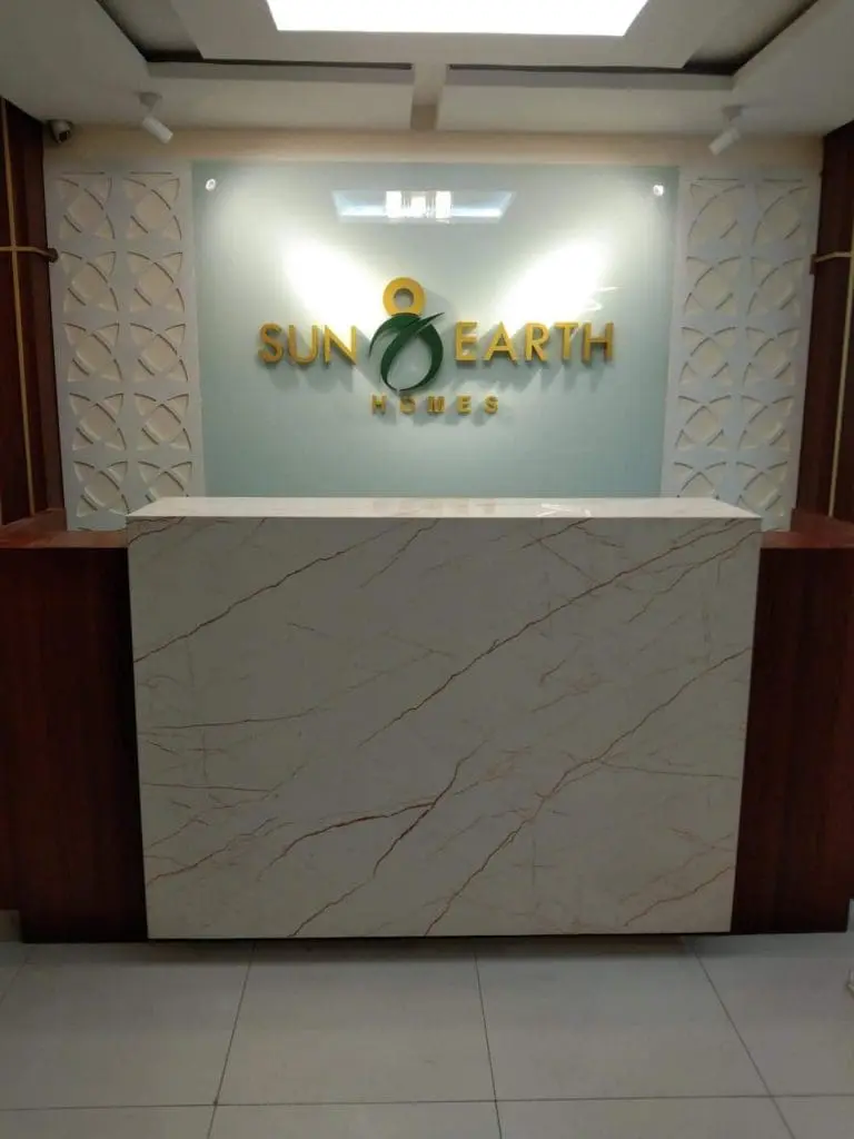 Acrylic gold metallic SUN EARTH HOMES signage at Makati reception area, marble counter, glass wall by M&G Global Ads.
