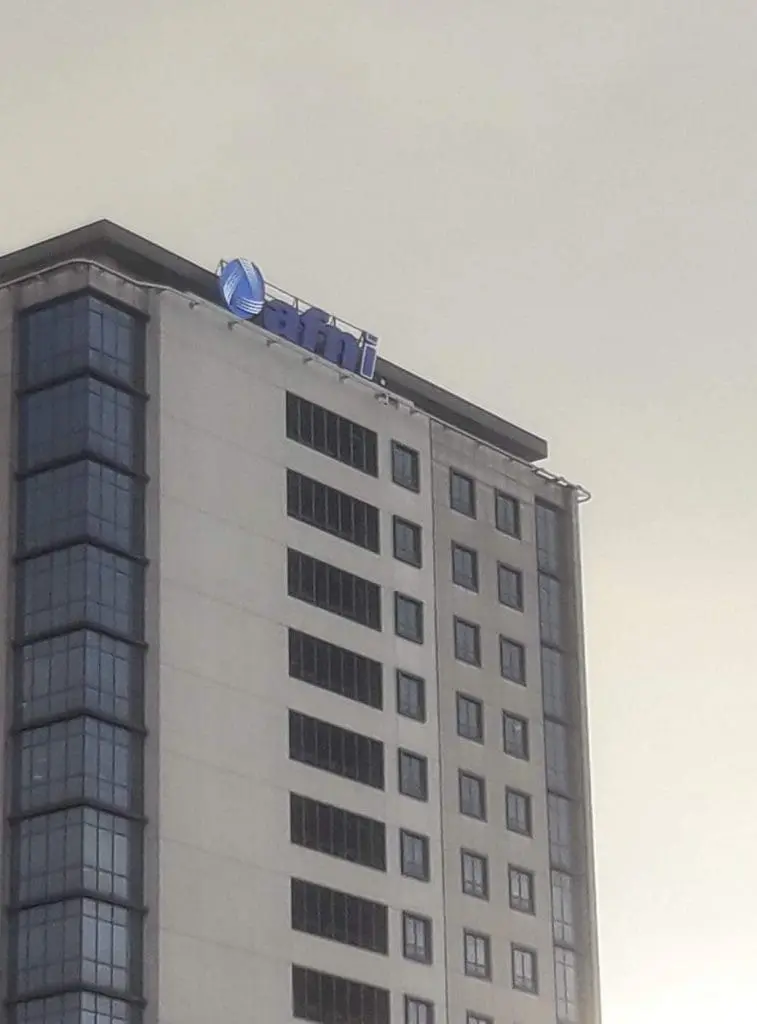 Acrylic building signage for ATTI on a tall modern office in Makati, blue and white logo at top, by M&G Global Ads.