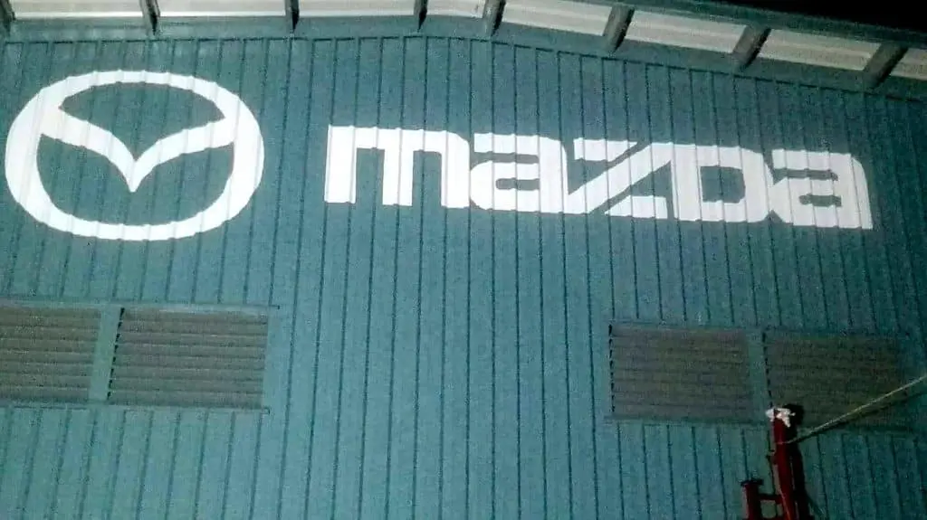 Mazda LED signage on blue corrugated metal building in Makati, with ventilation grates below; by M&G Global Ads.