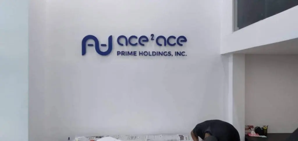 Blue metallic office signage for ace²ace PRIME HOLDINGS, INC. in Makati, white wall background, by M&G Global Ads.