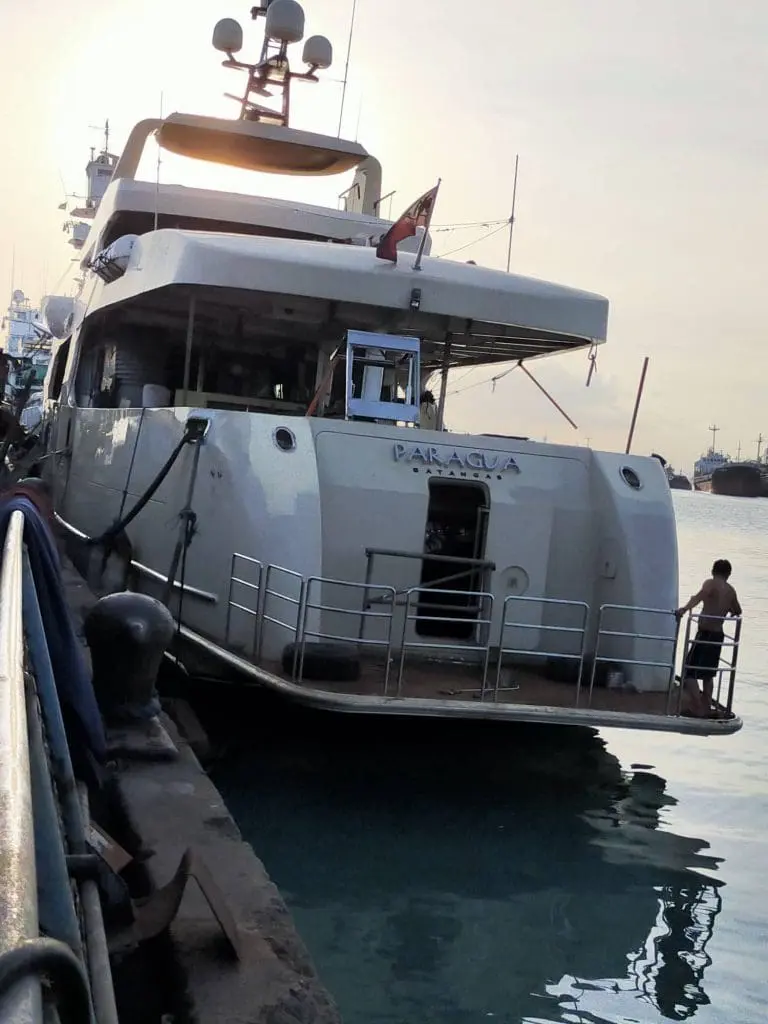 PARAGUA yacht with acrylic signage docked at pier, people on deck, sunset glow, BGC location by M&G Global Ads.