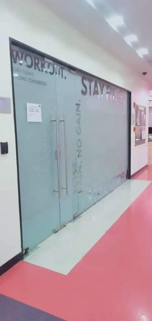 Motivational frosted glass door signage for a fitness center in Makati, with red and white floor tiles by M&G Global Ads.