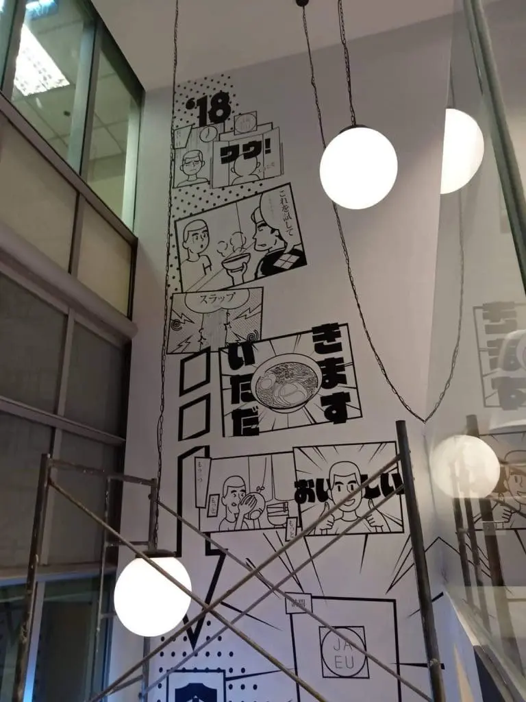 Acrylic signage and black-and-white comic mural with Japanese text in a Makati restaurant interior by M&G Global Ads.