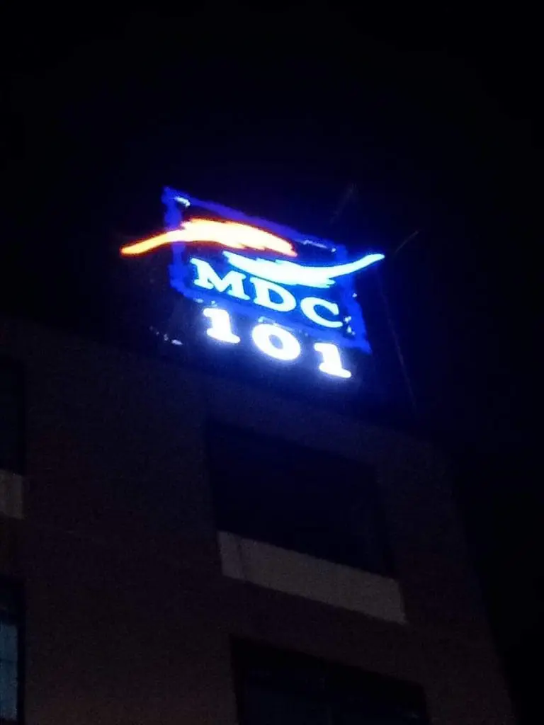 MDC 101 illuminated outdoor metal signage on a building at night in BGC, with red and blue wavy design by M&G Global Ads.