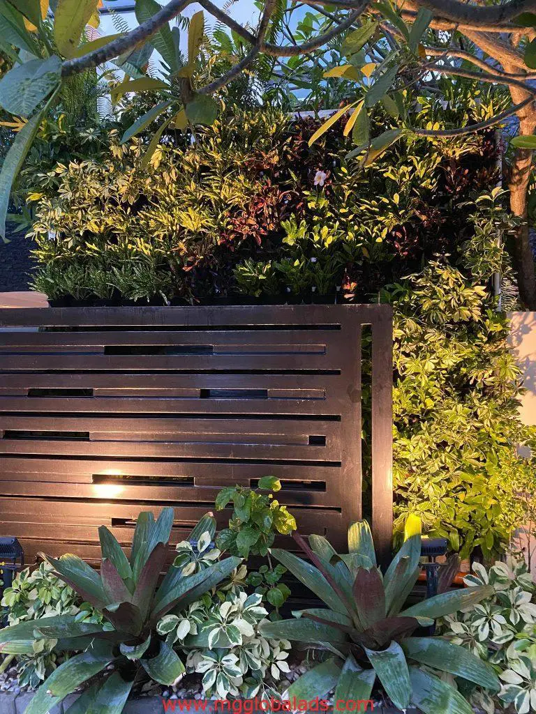 Modern black fence with LED signage at its base in Pasig, surrounded by lush plants and trees. By M&G Global Ads.